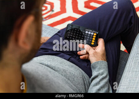 LONDON, UK - SEP 21, 2018: Man using the new Apple iPhone Xs with the immense OLED retina display and a12 bionic chip, looking over the app application using calculator calculations app scientific Stock Photo