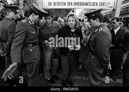 GDR border guards inspect the ID cards of GDR citizens, who return to East Berlin after visiting West Berlin. Border crossing point at Friedrichstrasse at the Allied control point Checkpoint Charlie in the district of Kreuzberg. Stock Photo
