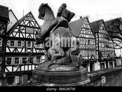 View of half-timbered houses from St. Andreas Church in the main street of Ochsenfurt. In the foreground, an equestrian statue of a knight. Undated photo. Stock Photo