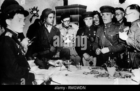 American man (middle of the picture with steel helmet and light trench coat) celebrates together with Russian soldiers at the meeting of the two armies in Torgau. Stock Photo