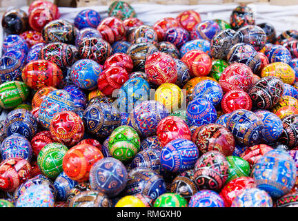 Multicolored painted eggs in wicker basket at market outdoors, easter holidays. Stock Photo