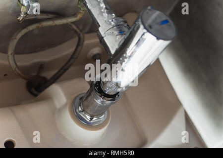 Leaking steel pipes under sink with water drops Stock Photo