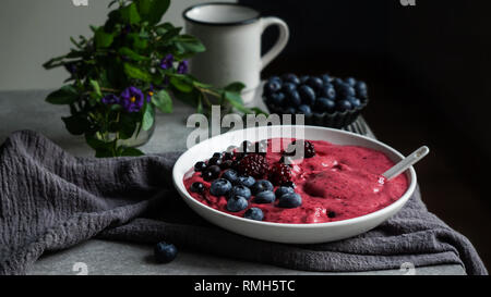 Smoothy of fresh bog blueberries and raspberries in bowl near napkin Stock Photo