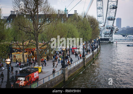 London, UK - April, 2018. View of a tourist crowded South Bank near Westminster with the London Eye on the background. Stock Photo