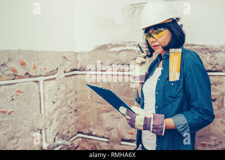 Female construction worker planning how to repairing bathroom pipes with  positive attitude. using a work tool. Stock Photo