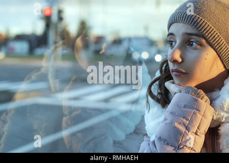 eenager girl.Girl teenager sits on the bus and looks out the window,teenager girl is sitting in the bus looking forward thinking. Stock Photo