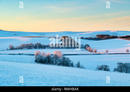 Snow covered winter landscape at sunrise in Avebury, Wiltshire, England Stock Photo