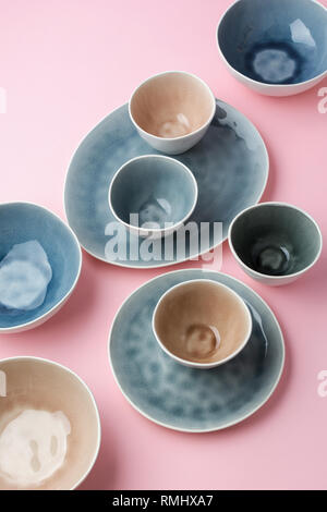 Beautiful blue, grey, beige dinnerware, plates bowls on pink table, top view, selective focus Stock Photo