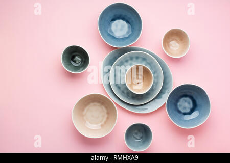 Beautiful blue, grey, beige dinnerware, plates bowls on pink table, top view, selective focus Stock Photo