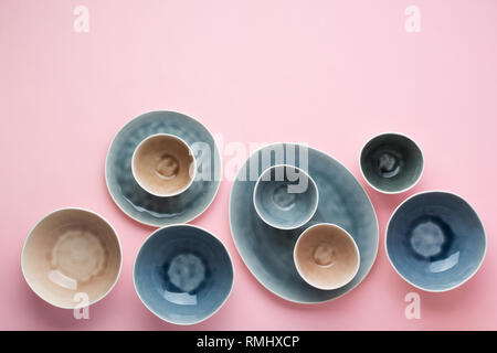 Beautiful blue, grey, beige dinnerware, plates bowls on pink table, top view, selective focus Stock Photo