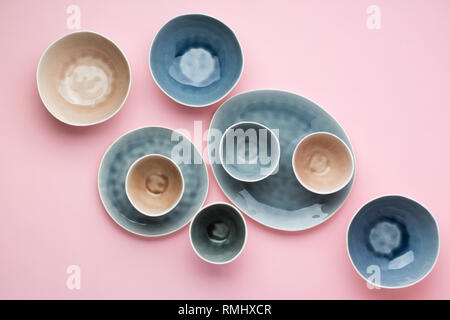 Beautiful blue, grey, beige dinnerware, plates bowls on pink table, top view, selective focus Stock Photo