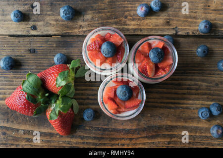 Homemade strawberry yogurt with jam and pieces of fruit on a wooden board. View from above
