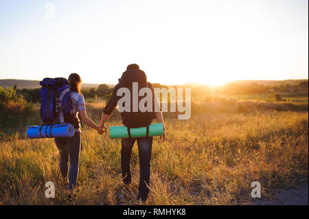 travelers with backpack walking in sunset. Back view. Stock Photo