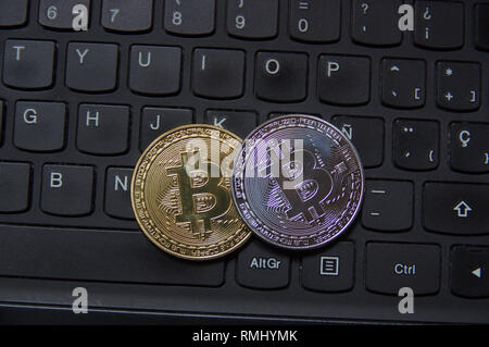 Bitcoin coins one gold and one silver over a black laptop qwerty keyboard Stock Photo