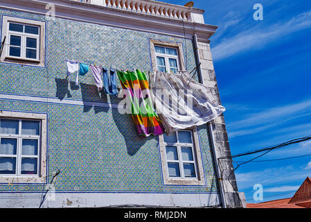 dry laundry on the window on a covered tiled facade of azulejos in the district of Alcantara, Lisbon, Portugal Stock Photo