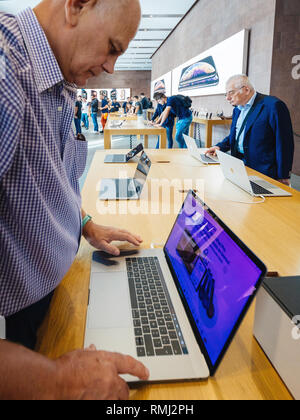 STRASBOURG, FRANCE - SEP 21, 2018: Side view of two seniors men testing Aplle MacBook Pro 15 2018 laptops in Apple Store - latest laptop features a new Intel CPU , 4tb NVME SSD and 32 GB Ram Stock Photo