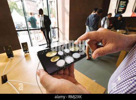 STRASBOURG, FRANCE - SEP 21, 2018: Senior man using drums in GarageBand music creation app on the iphone Xs Max during launch day in the Apple Store Stock Photo