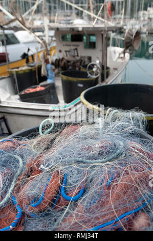 Close up on colored fishing nets. In the background a blurred fishing boat Stock Photo