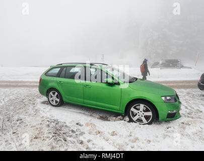 MUMMELSEE, GERMANY - JAN 26, 2019: Woman parking green Skoda Octavia RS car Combi estate car in snow covered parking - bad weather in Black Forest Mountains  Stock Photo