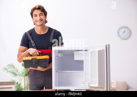 Young handsome contractor repairing fridge Stock Photo