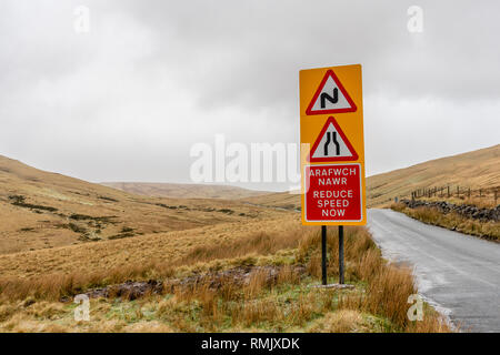 Double bend, narrowing road on both sides and reduce speed now (Welsh: Arafwch Nawr) signs in the Brecon Beacons National Park, Wales, UK Stock Photo