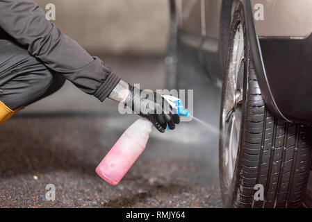 Professional car washer cleaning car alloy wheels . Stock Photo