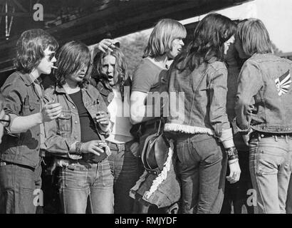 Teenagers, mostly wearing denim, stand in a group. Stock Photo