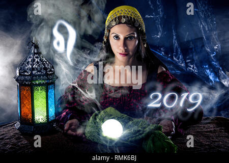 Psychic or fortune teller with crystal ball and horoscope zodiac sign of Leo Stock Photo