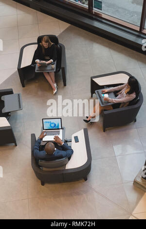 People using multimedia devices in the lobby Stock Photo
