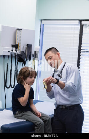 Young asian male doctor showing ear model to caucasian boy patient in clinic Stock Photo