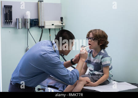 Young asian male doctor examining caucasian boy patient with tool in a clinic Stock Photo
