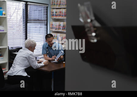 Young Asian male doctor and senior patient discussing over digital tablet Stock Photo