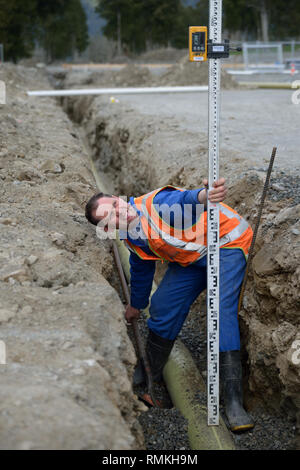 A tradesman checks the depth of a new stormwater drain Stock Photo