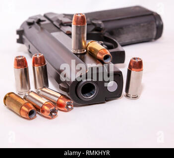 A black 40 caliber pistol with eight 40 caliber hollow point bullets on a white background Stock Photo