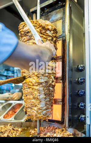 Chef cutting traditional Turkish food Shawarma chicken Doner Kebab in the outdoor restaurant Stock Photo