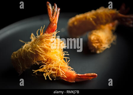 Four Japanese Tempura style prawns served on a grey plate as a starter Stock Photo