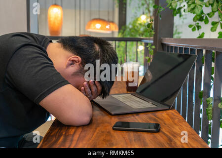Tired man sleeping in front of laptop Stock Photo