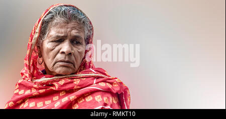 Beautiful photo of Old Aged Indian Woman farmer in her late 70s wearing red robe, in sad mood, because of poor harvest and losing her valuable assets Stock Photo