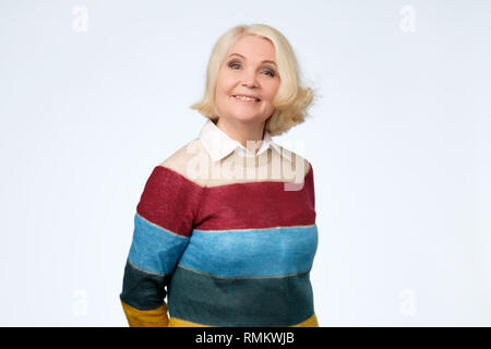 Senior caucasian woman with blonde hair in colored sweater smiling Stock Photo