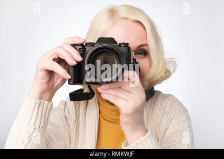Senior blonde woman taking photo with camera Stock Photo