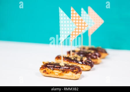 Food, desserts and bakery concept - traditional french eclairs with decorative flags on blue-white background Stock Photo