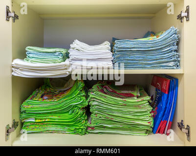 Interior of white plastic cabinet or clothing wardrobe with open doors with stacked pile of clean colorful linen. Household and order, furniture desig Stock Photo