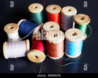 Natural silk threads on wooden spools of different colors. Stock Photo