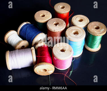 Natural silk threads on wooden spools of different colors. Stock Photo