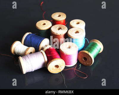 Natural silk threads on wooden spools of different colors. Stock Photo