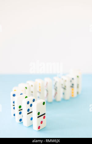 White dominos with brightly colored dots lined up in a curving series Stock Photo