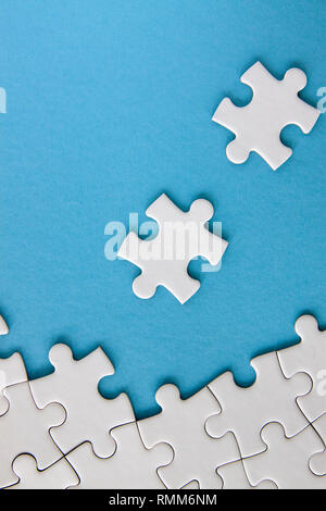 White jigsaw puzzle pieces on blue background Stock Photo