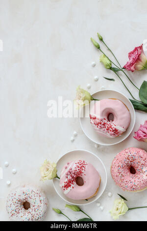 Flat lay composition with pink donuts and flowers on a bright background Stock Photo
