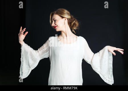 Close up studio portrait of beautiful woman in a white dress against black background Stock Photo