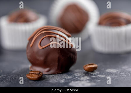 Set of luxury chocolate candies with coffee filling decorated with caramel splashes. Exclusive handmade bonbons on wooden background. Macro. Stock Photo